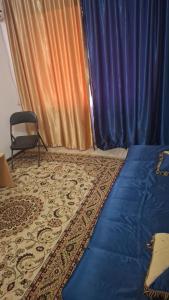 a bedroom with a bed and a chair and curtains at Махамбета in Atyrau