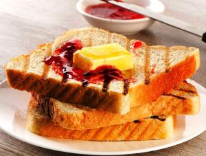 two pieces of toast with jam and butter on a plate at homly hotel in Indore