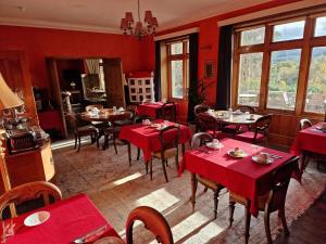 a restaurant with red tables and chairs and windows at Cambus O' May Traditional Highland Hotel in Ballater