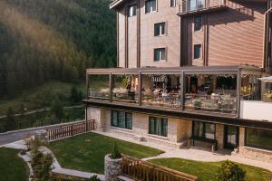 a building with a balcony with people sitting on it at Chalet Valdotain in Breuil-Cervinia