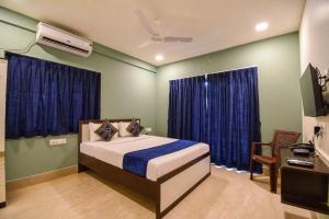 a bedroom with a bed and a desk and a television at FabHotels Calyra in Karīmnagar