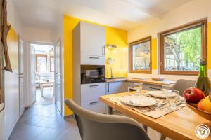 a kitchen with yellow walls and a wooden table and chairs at Le clos bambou in Loueuse