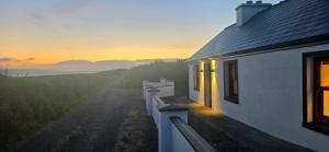 a house with the sunset in the background at Bunowen, Louisburgh, Walk to the Beach! in Louisburgh