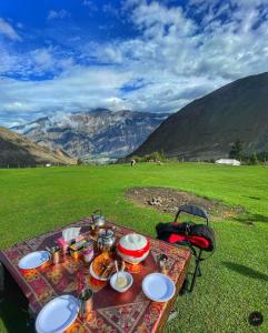a picnic table with food on it in a field at Hello Rakaposhi Camping Site in Gilgit