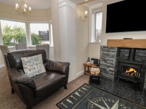 a living room with a leather chair and a fireplace at Roma in Rhos-on-Sea