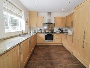 a large kitchen with wooden cabinets and a window at Roma in Rhos-on-Sea