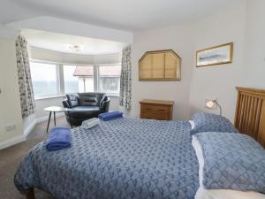 a bedroom with a blue bed and a chair at Roma in Rhos-on-Sea
