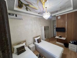a bedroom with two beds and a chandelier at Bella Hotel Navoi in Karmana