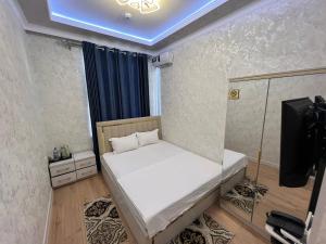 a small bedroom with a bed and a television at Bella Hotel Navoi in Karmana +2 photos