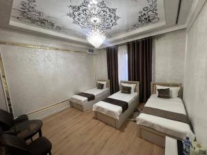 a room with three beds and a chandelier at Bella Hotel Navoi in Karmana