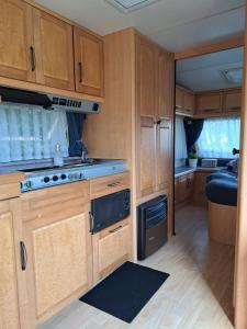 a kitchen with wooden cabinets and a stove at Camping de Zandhorst, Toercaravan Fendt in Wouterswoude