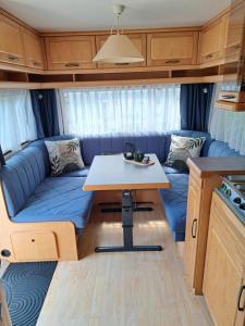 a living room with a blue couch in a caravan at Camping de Zandhorst, Toercaravan Fendt in Wouterswoude