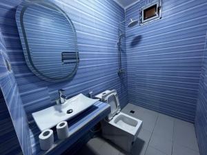 a blue bathroom with a sink and a toilet at Sall Africa Tourisme in Mbour