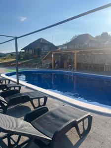 a swimming pool with lounge chairs next to a house at Šebovina Jelova gora in Starčevići