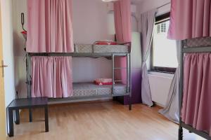 two bunk beds in a room with pink curtains at Drenak Hostel in Skopje