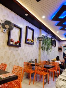 a dining room with orange chairs and a table and chairsktop at Hotel Vishnu Priya Ayodhya in Ayodhya