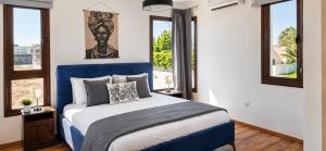 a bedroom with a blue and white bed and windows at Palm Tree Villa By Staycom in Oroklini +13 photos