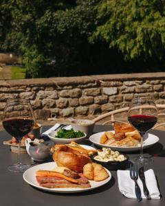 a table with plates of food and two glasses of wine at Aysgarth Falls Hotel & Restaurant in Aysgarth
