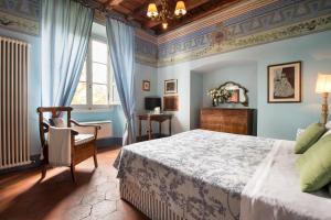 a bedroom with a bed and a chair at Relais Villa Belpoggio - Residenza D'Epoca in Loro Ciuffenna
