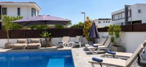 a patio with chairs and an umbrella and a pool at Palm Tree Villa By Staycom in Oroklini