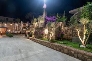a stone fence with purple flowers and a stone wall at Moncler Residence in Ksamil