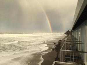 a rainbow over the ocean with a building at Sandcastle Beachfront in Lincoln City