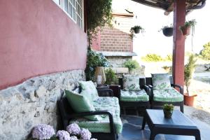a patio with chairs and tables and a pink wall at Casa da Juana in Chantada