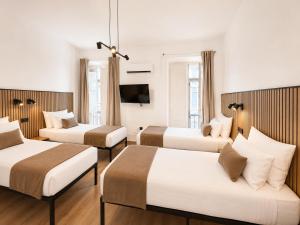 a hotel room with three beds and a flat screen tv at Casa Antares Granada in Granada