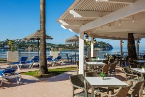 a patio with tables and chairs and the water at TRH Jardín Del Mar in Santa Ponsa