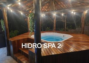 an outdoor hot tub in a wooden deck with a roof at Pousada do Rodrigo in Macacos