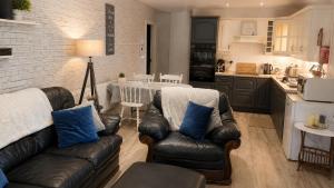 a living room with two leather couches and a kitchen at Farm Lodge in Monaghan