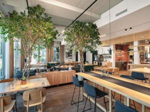 a restaurant with tables and chairs and trees at Oru Hub Hotel Tallinn - Handwritten Collection in Tallinn