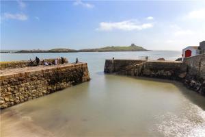 a group of people standing on a wall in the water at Biddy's Cottage Dalkey in Dublin