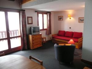 a living room with a red couch and a tv at Saint-Roch Piste in Val dʼIsère