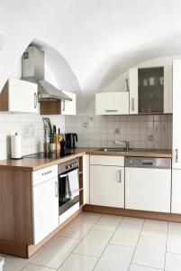 a kitchen with white cabinets and a stove top oven at Heritage Courtyard Apartment in Bruck an der Leitha