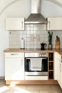 a kitchen with white cabinets and a stove top oven at Heritage Courtyard Apartment in Bruck an der Leitha