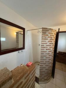 a bathroom with a mirror and a brick wall at Pousada Maraí in Amontada