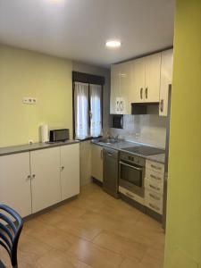 a small kitchen with white cabinets and appliances at Plazacuervo in Pancorbo