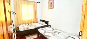 two beds in a room with a window at Dans place in Moshi