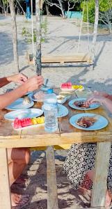 a wooden table with plates of food on it at Nilaveli Eco Lodge in Nilaveli