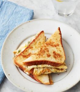 two grilled cheese sandwiches on a plate with a glass of milk at River cliff guest house in Gunungsriti