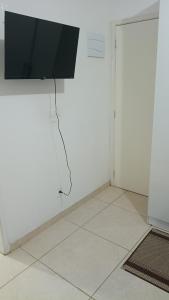 a living room with a tv on a white wall at Hostel Viracopos in Campinas
