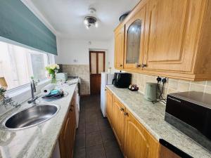 a kitchen with wooden cabinets and a sink at Bolton Terrace - 2 Bedrooms - Sleeps 4 in Workington +30 photos
