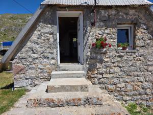 a small stone building with a door and stairs at Miris Katuna - Sinjajevina in Šavnik