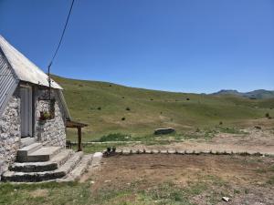 a stone building with stairs next to a hill at Miris Katuna - Sinjajevina in Šavnik