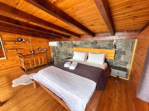 a bedroom with a large bed in a log cabin at Novella Bungalov in Işıklı