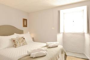 a bedroom with a bed with white sheets and a window at Casa da Juana in Chantada