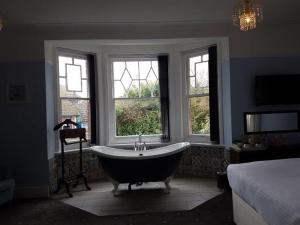 a bathroom with a tub in a room with windows at Seabrook House Hotel in Hythe