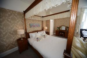 a bedroom with a canopy bed and a desk at Seabrook House Hotel in Hythe