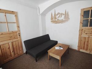 a living room with a black couch and a table at Apartmán U Krtka in Lázně Kynžvart